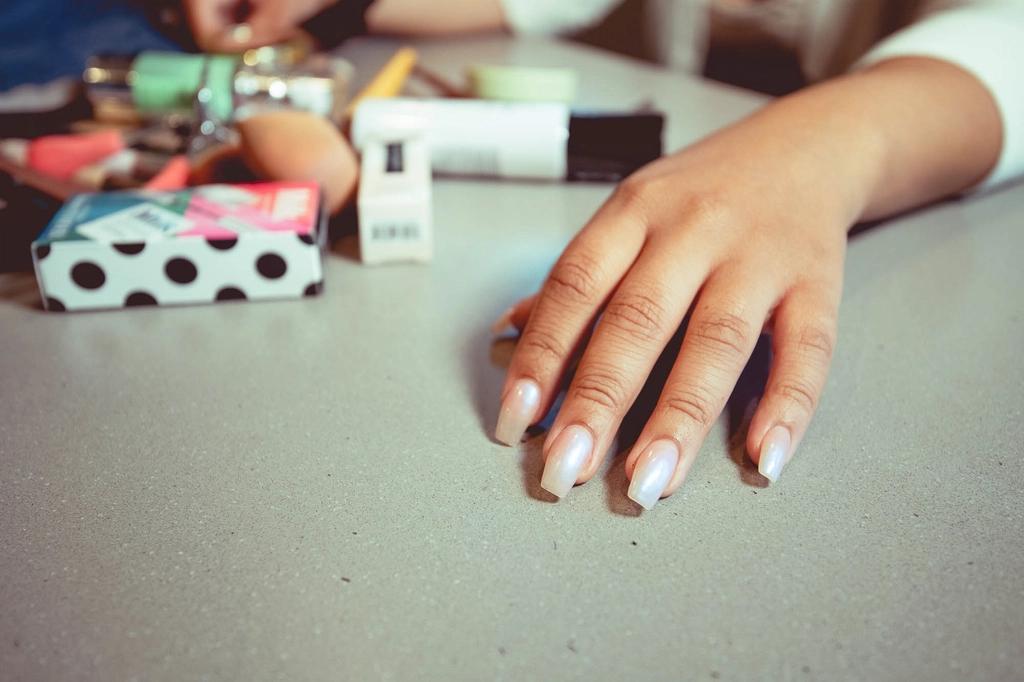 Mano con uñas pintadas sobre una mesa de manicura